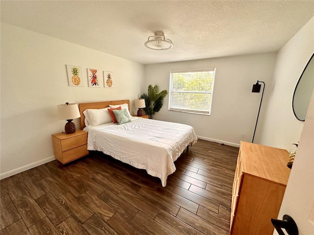 bedroom with a textured ceiling, baseboards, and dark wood finished floors