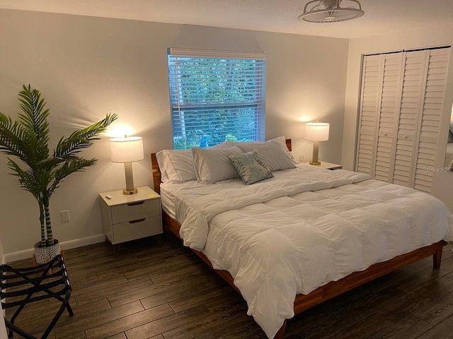 bedroom featuring baseboards, a closet, and dark wood-type flooring