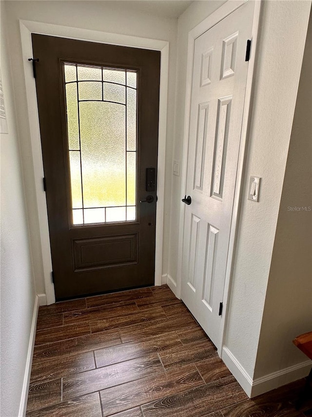doorway featuring dark wood-style floors and baseboards