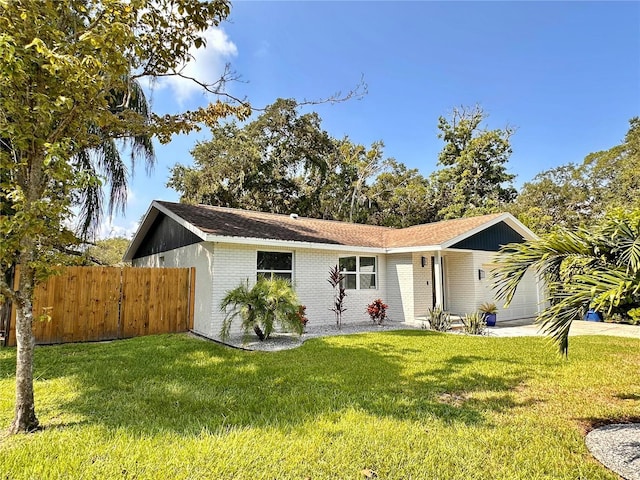 single story home featuring brick siding, fence, a front yard, concrete driveway, and an attached garage