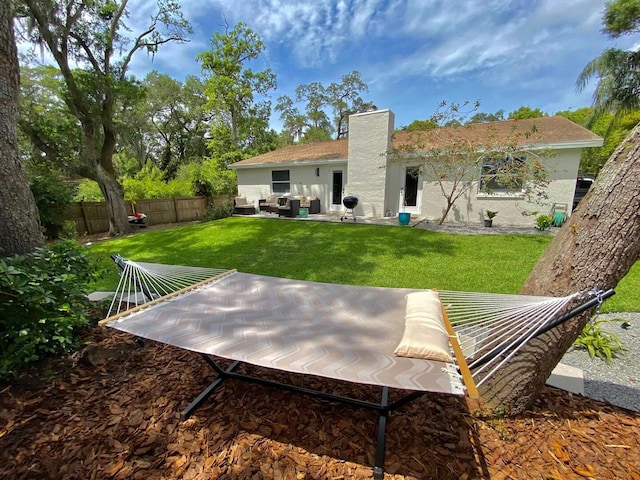 back of house with a patio area, a yard, a fenced backyard, an outdoor hangout area, and stucco siding