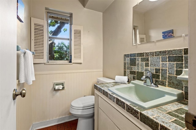 bathroom featuring toilet, decorative backsplash, and vanity