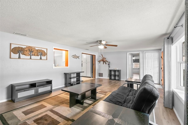 living room featuring a textured ceiling, ceiling fan, and light hardwood / wood-style floors