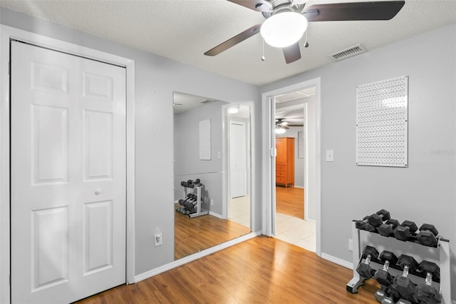 exercise area with a textured ceiling, ceiling fan, and hardwood / wood-style flooring