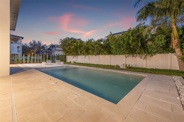 pool at dusk featuring a patio