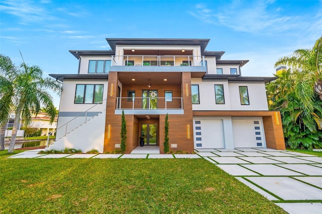 view of front of home with a balcony, a garage, and a front yard