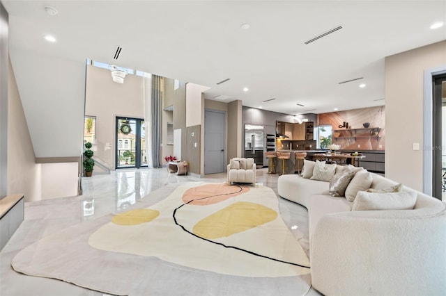 living room with wooden walls, recessed lighting, an accent wall, visible vents, and marble finish floor