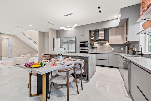 kitchen featuring stainless steel appliances, tasteful backsplash, a sink, modern cabinets, and wall chimney exhaust hood