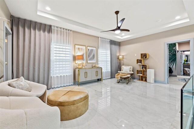 interior space featuring a tray ceiling, light tile patterned floors, and ceiling fan