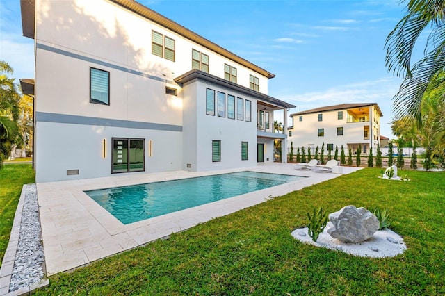 rear view of property with an outdoor pool, fence, a yard, a patio area, and stucco siding