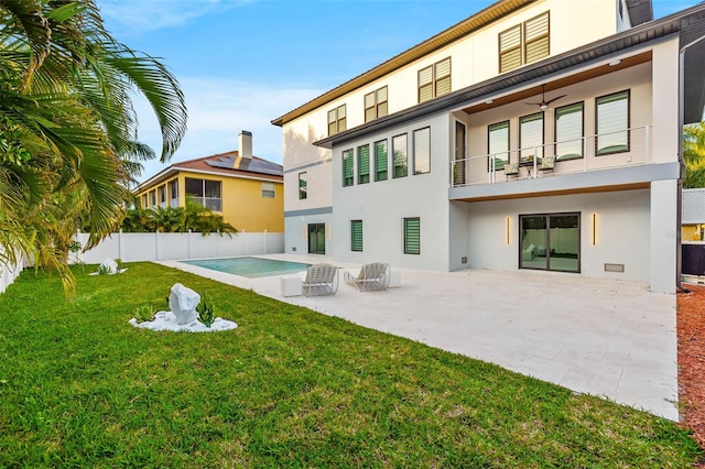 back of house featuring a patio area, a lawn, a balcony, and stucco siding