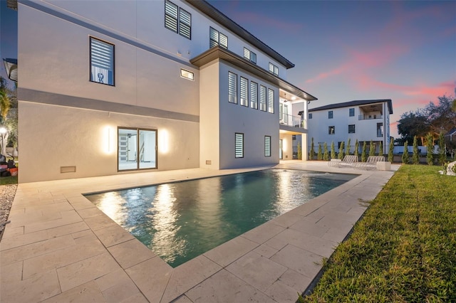 pool at dusk featuring a patio