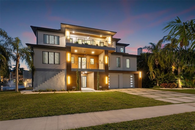 contemporary home with a balcony, a yard, and a garage