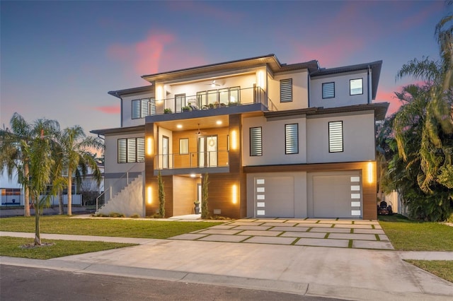 view of front facade with a lawn, a balcony, an attached garage, and stucco siding