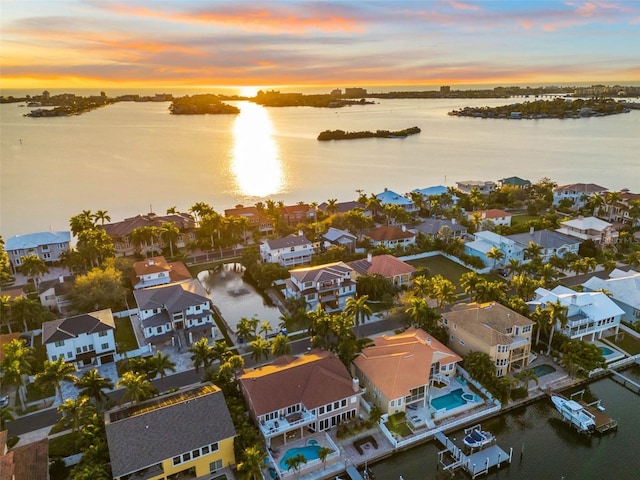 aerial view at dusk featuring a residential view and a water view