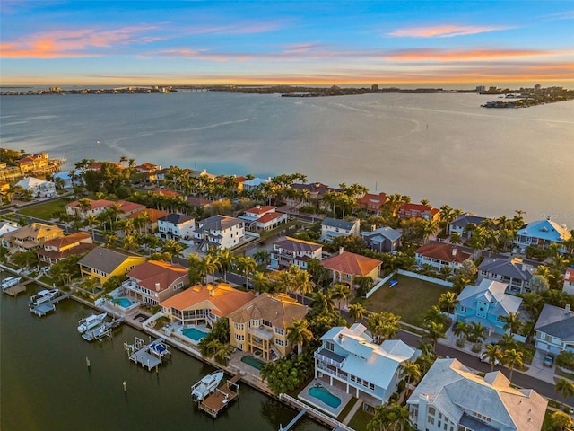 aerial view at dusk featuring a residential view and a water view