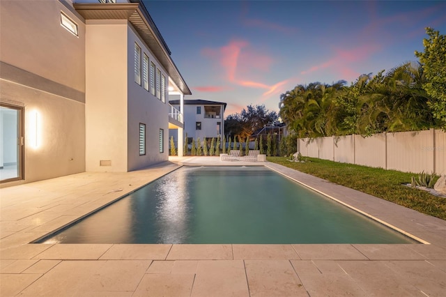 pool at dusk featuring a patio area, fence, and a fenced in pool