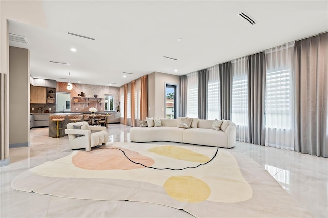 living area featuring marble finish floor, plenty of natural light, and visible vents