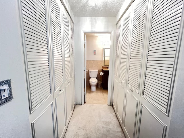 corridor featuring a textured ceiling and light carpet