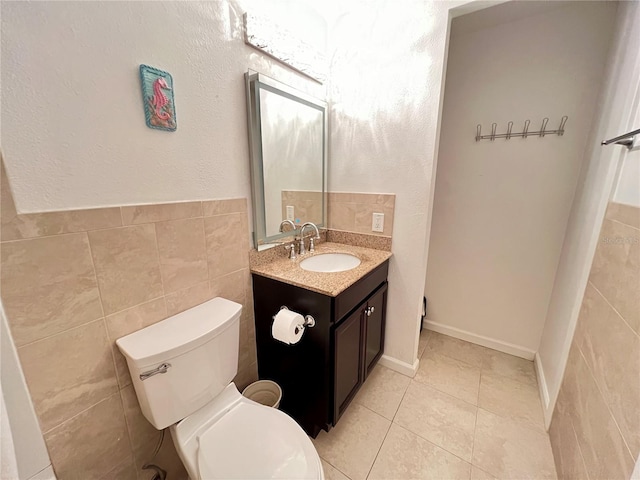 bathroom featuring tile patterned floors, toilet, vanity, and tile walls