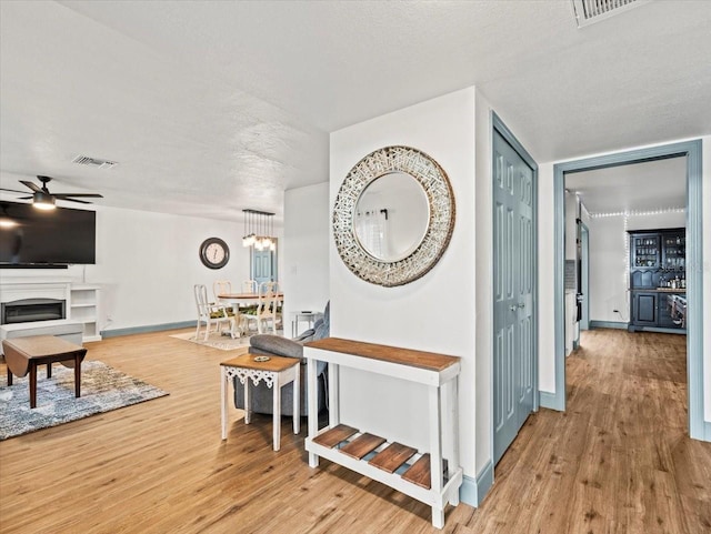 corridor featuring light hardwood / wood-style floors, a textured ceiling, and a chandelier