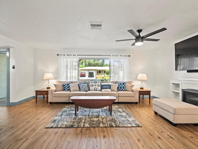 living room featuring a textured ceiling, ceiling fan, and light wood-type flooring