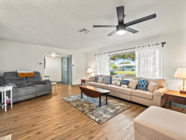 living room featuring ceiling fan, light hardwood / wood-style floors, and a textured ceiling