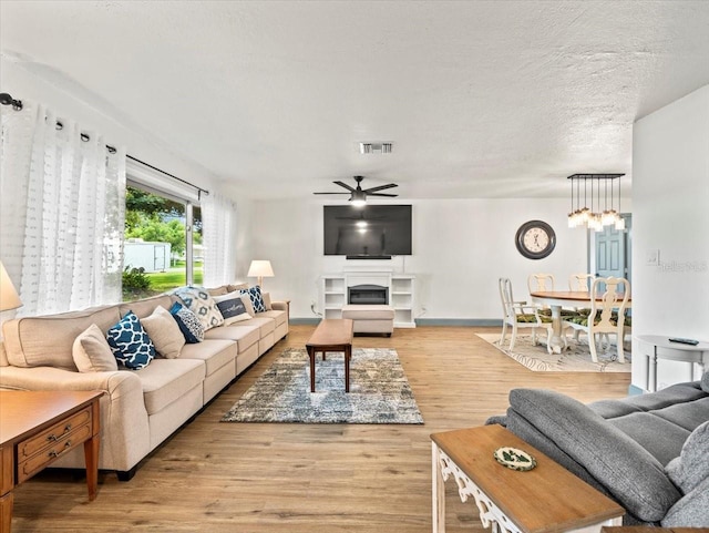 living room with ceiling fan, a textured ceiling, and light hardwood / wood-style flooring