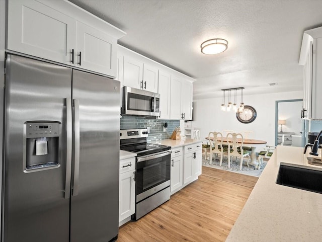 kitchen with light hardwood / wood-style floors, appliances with stainless steel finishes, and white cabinetry