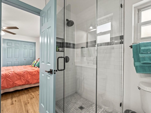 bathroom with ceiling fan, wood-type flooring, toilet, and a shower with shower door