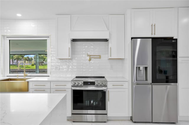 kitchen with custom range hood, white cabinetry, light stone countertops, and stainless steel appliances