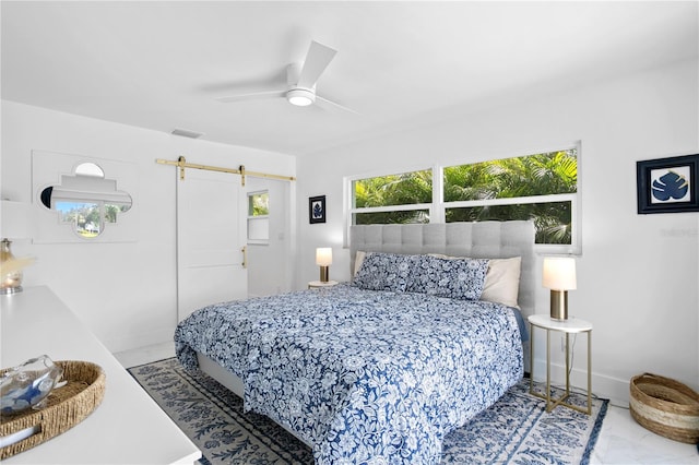 bedroom with ceiling fan, a barn door, and light tile patterned floors