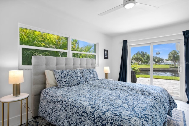 bedroom featuring access to exterior, ceiling fan, and a water view