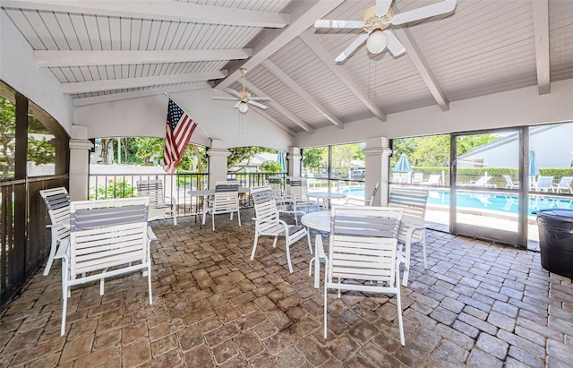 unfurnished sunroom with ceiling fan and vaulted ceiling with beams