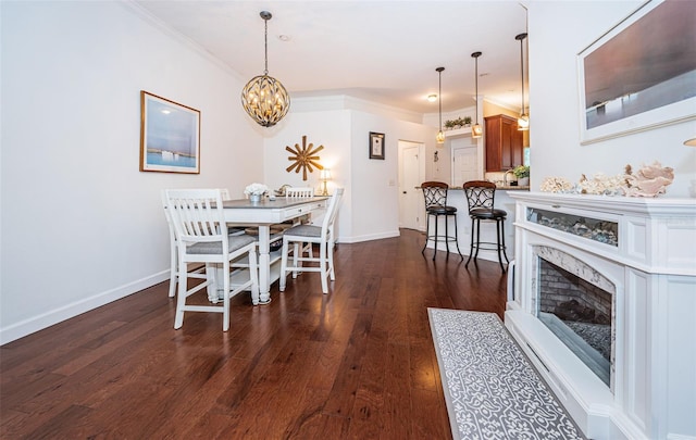 dining room featuring an inviting chandelier, a premium fireplace, dark hardwood / wood-style flooring, and ornamental molding