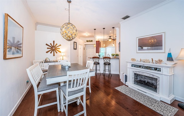 dining space with a fireplace, crown molding, an inviting chandelier, and dark hardwood / wood-style floors