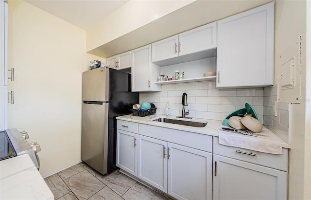 kitchen featuring decorative backsplash, white cabinets, stainless steel refrigerator, light tile patterned floors, and sink