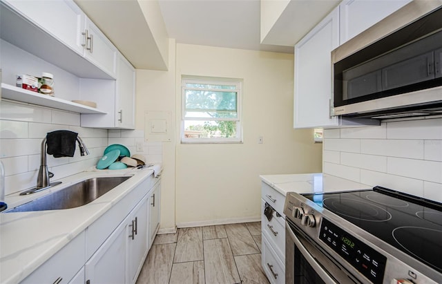 kitchen with sink, white cabinetry, backsplash, and stainless steel appliances