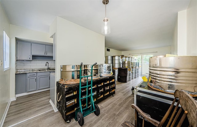 kitchen with pendant lighting, tasteful backsplash, gray cabinetry, light hardwood / wood-style floors, and sink