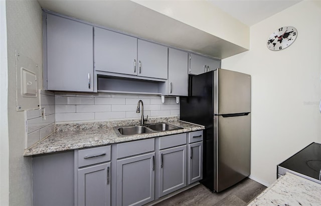 kitchen with backsplash, gray cabinets, dark hardwood / wood-style flooring, sink, and stainless steel fridge