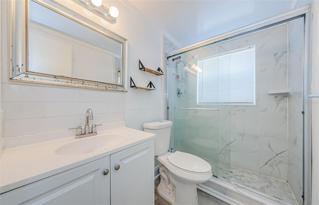 bathroom with tile walls, a shower with door, vanity, and toilet