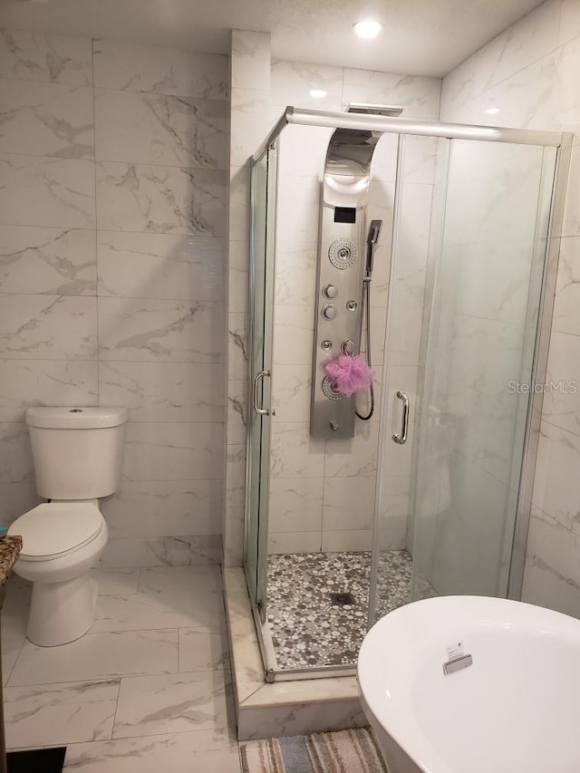 bathroom featuring tile walls, tile patterned flooring, toilet, and a shower with shower door