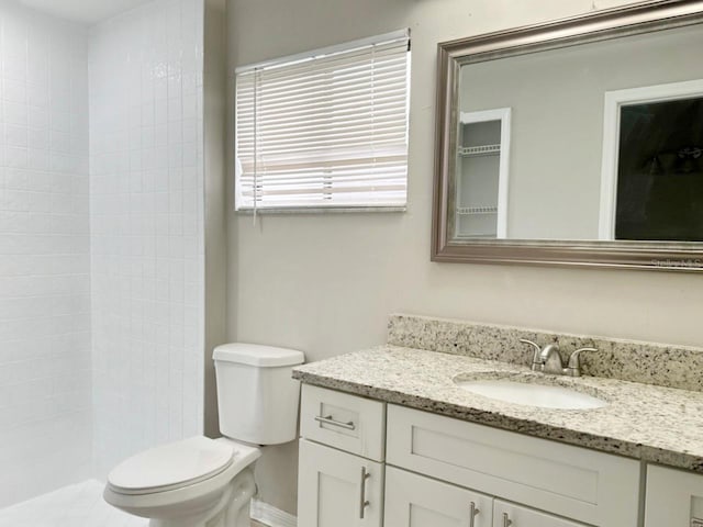 full bathroom featuring vanity, toilet, and a tile shower