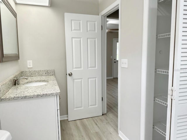 bathroom with visible vents, vanity, baseboards, and wood finished floors