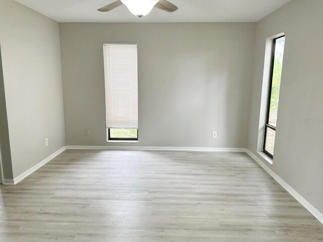 empty room featuring ceiling fan, light wood-type flooring, and a healthy amount of sunlight