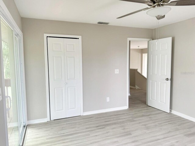 unfurnished bedroom with light hardwood / wood-style flooring, ceiling fan, and a closet