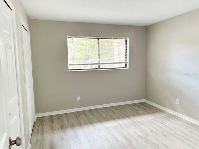 unfurnished bedroom featuring wood finished floors, baseboards, and a closet