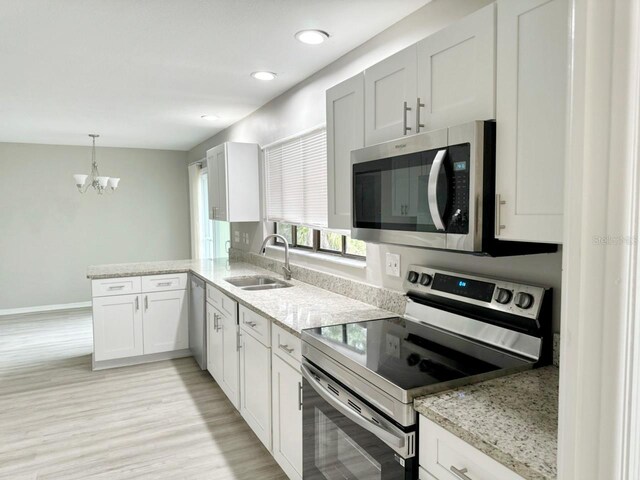 kitchen with light hardwood / wood-style flooring, a chandelier, sink, kitchen peninsula, and stainless steel appliances