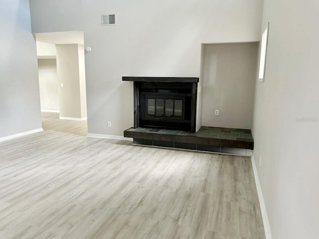 unfurnished living room featuring visible vents, a fireplace, baseboards, and wood finished floors