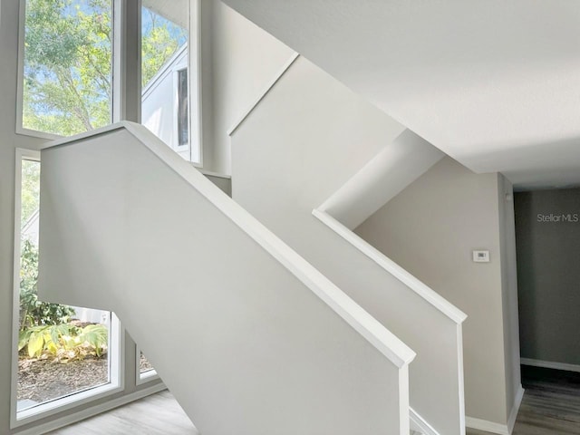 stairway with a healthy amount of sunlight, baseboards, and wood finished floors